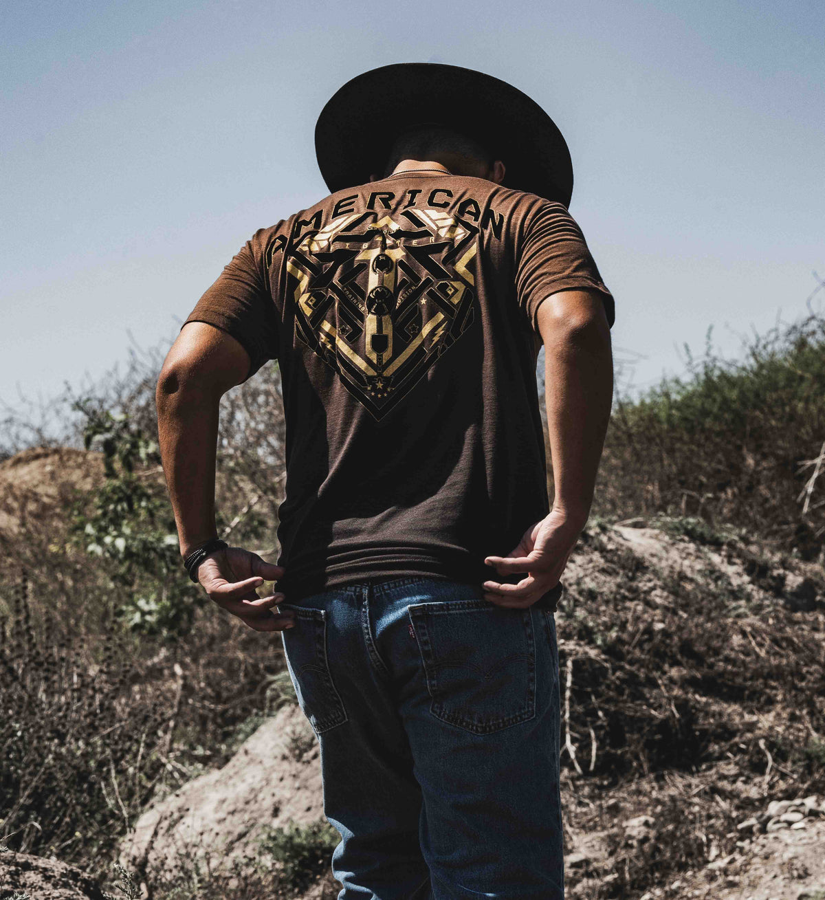 Person wearing a brown t-shirt with a graphic design outdoors