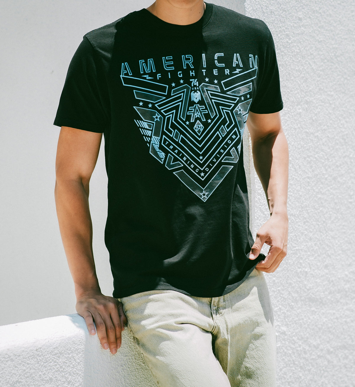 Person wearing a black t-shirt with 'American Fighter' logo on a light gray background
