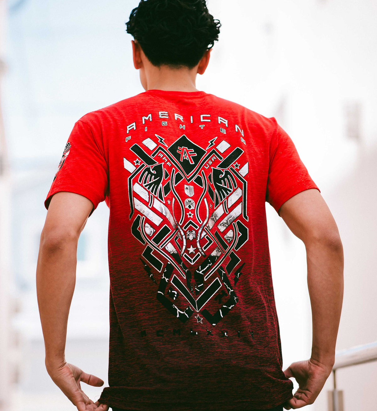 Person wearing a red t-shirt with a graphic design on the back, standing against a blurred background.