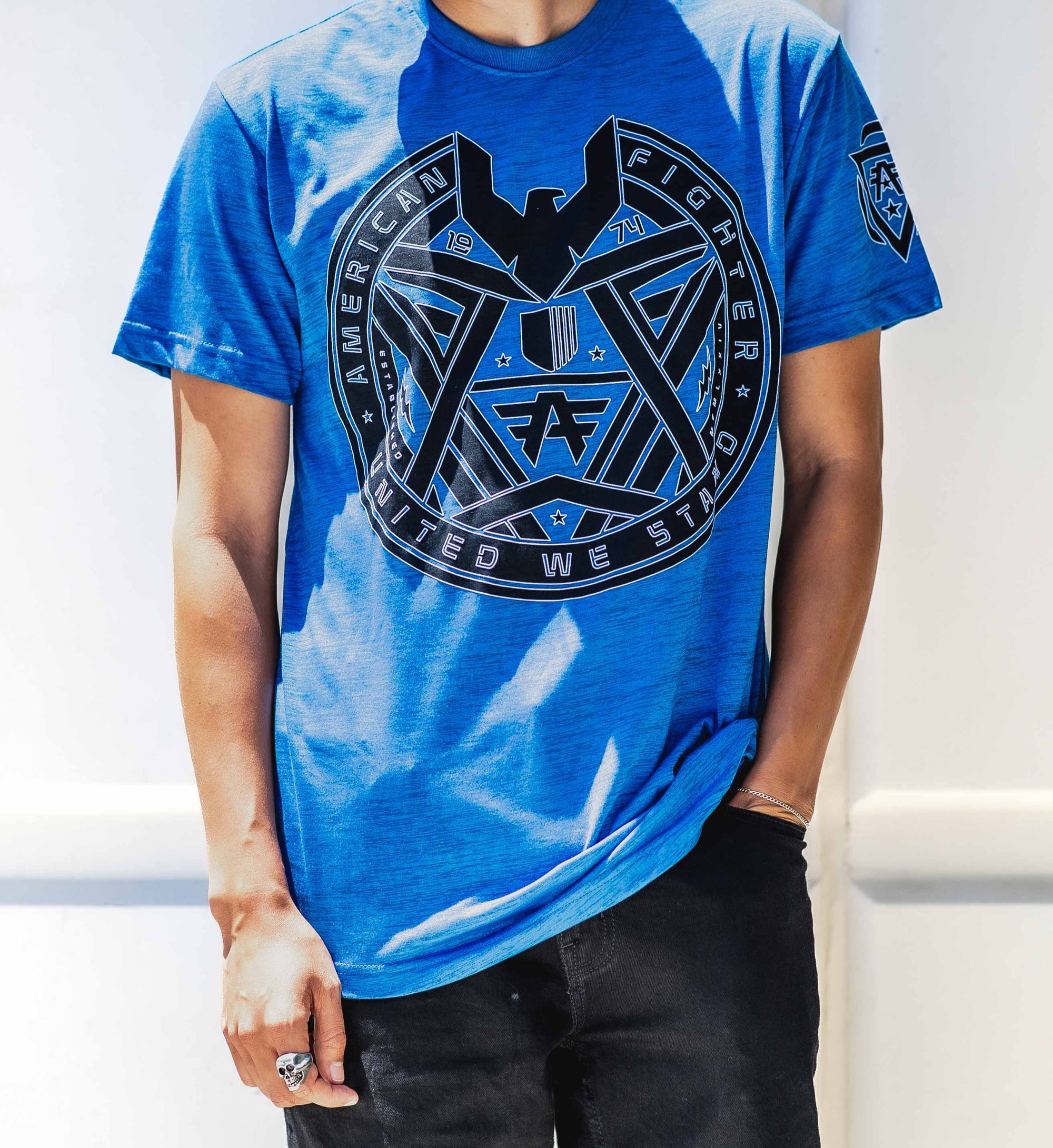 A male model wearing a blue short-sleeved t-shirt with a graphic print on the front.