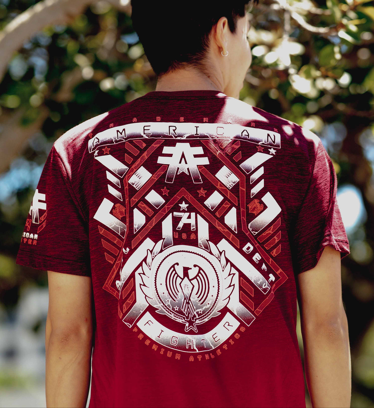 Person wearing a red t-shirt with a detailed design on the back, standing outdoors.