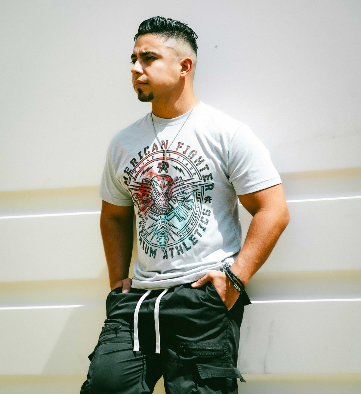 Man wearing a white t-shirt with graphic design and black cargo pants against a white background