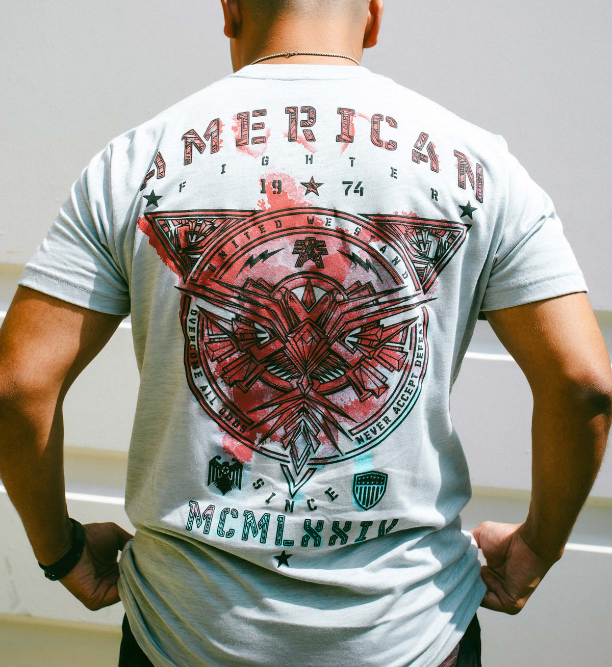 Person wearing a white t-shirt with red and black graphic design on the back