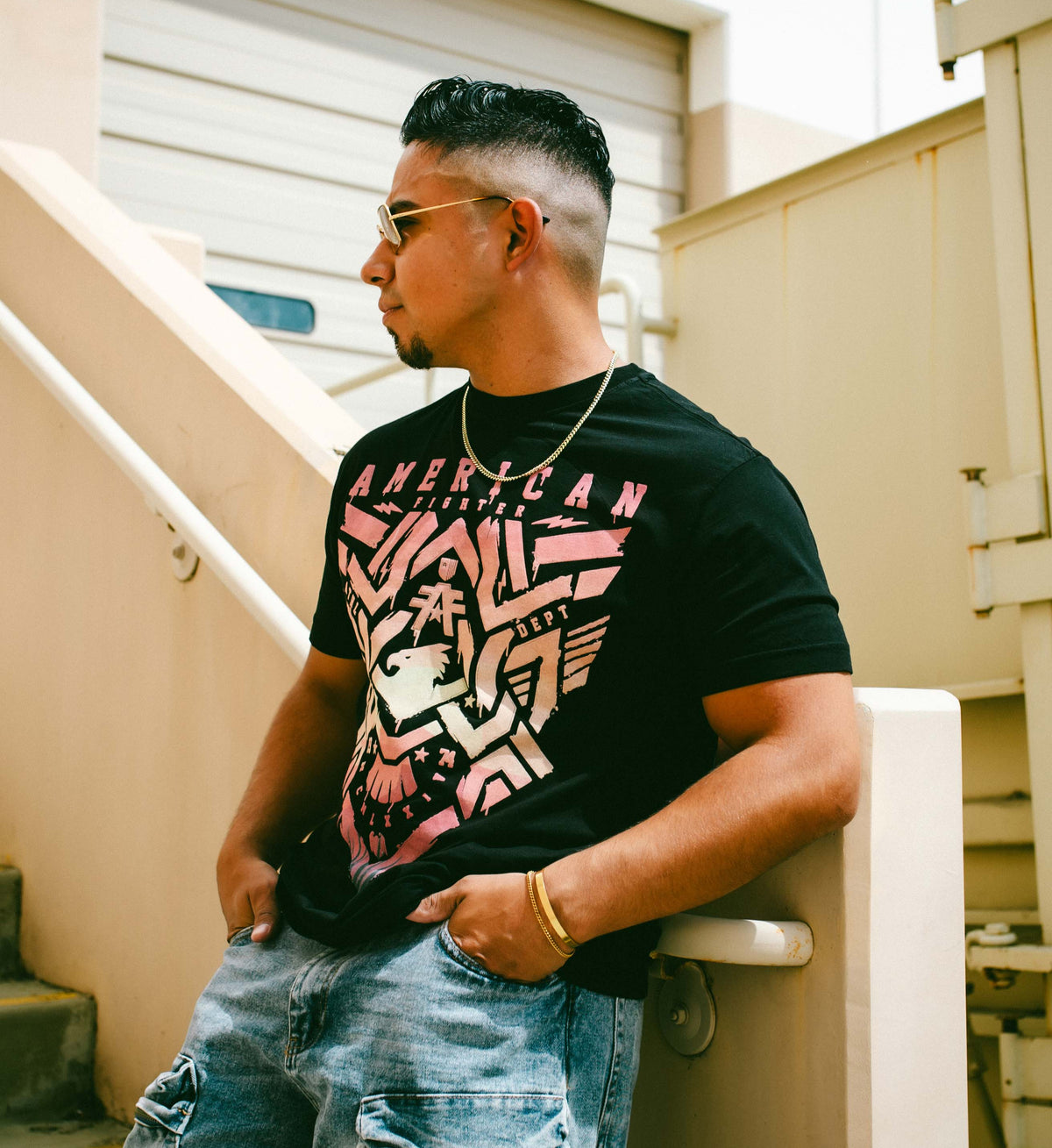 Man wearing a black t-shirt with colorful graphics and text, standing outdoors.