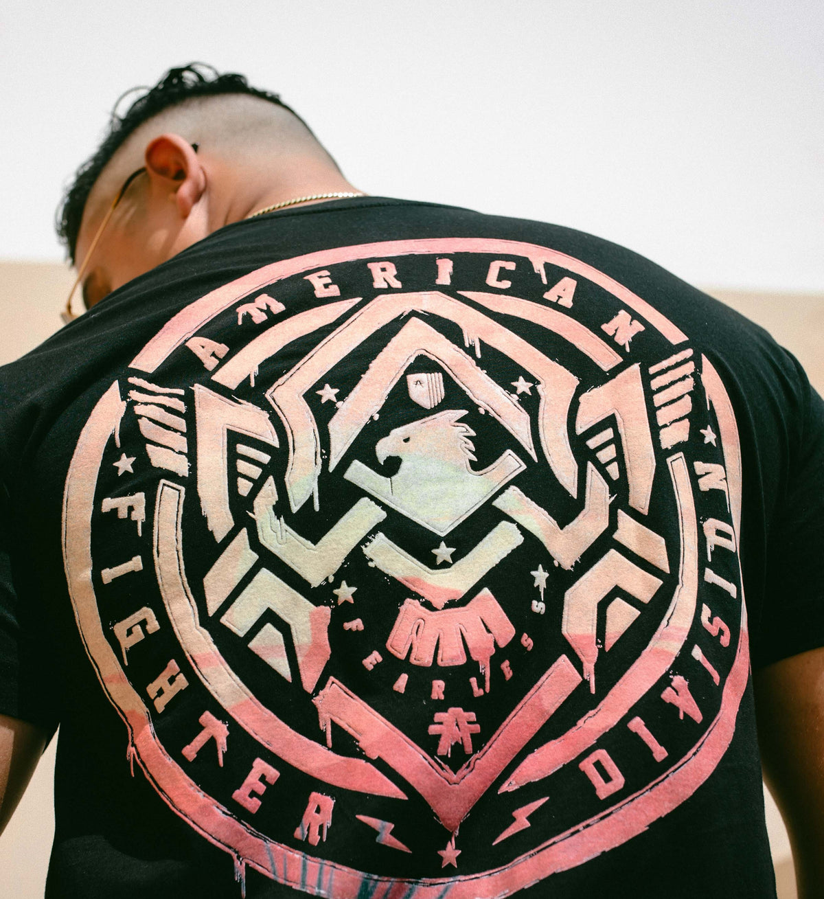 Person wearing a black t-shirt with a pink and white graphic design on the back.