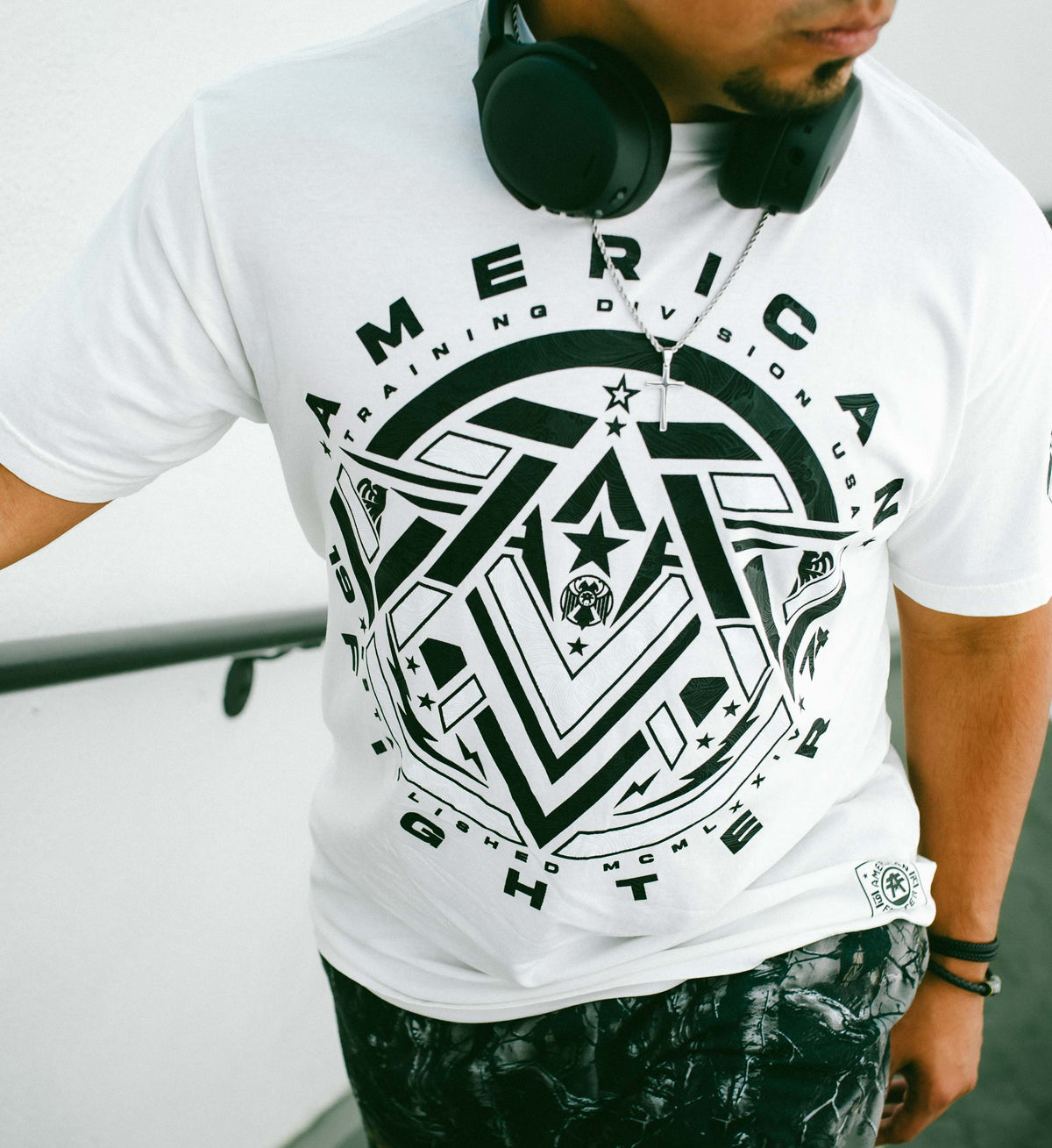 Person wearing a white t-shirt with black geometric design and text.