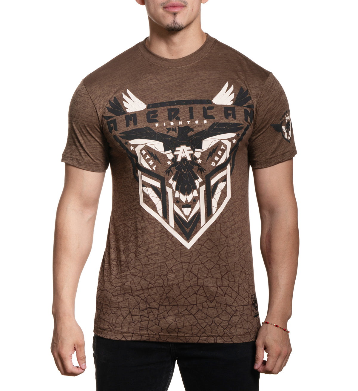 A male model wearing a brown short-sleeved t-shirt with a graphic print of a bull and the word 'AMERICAN' on it.