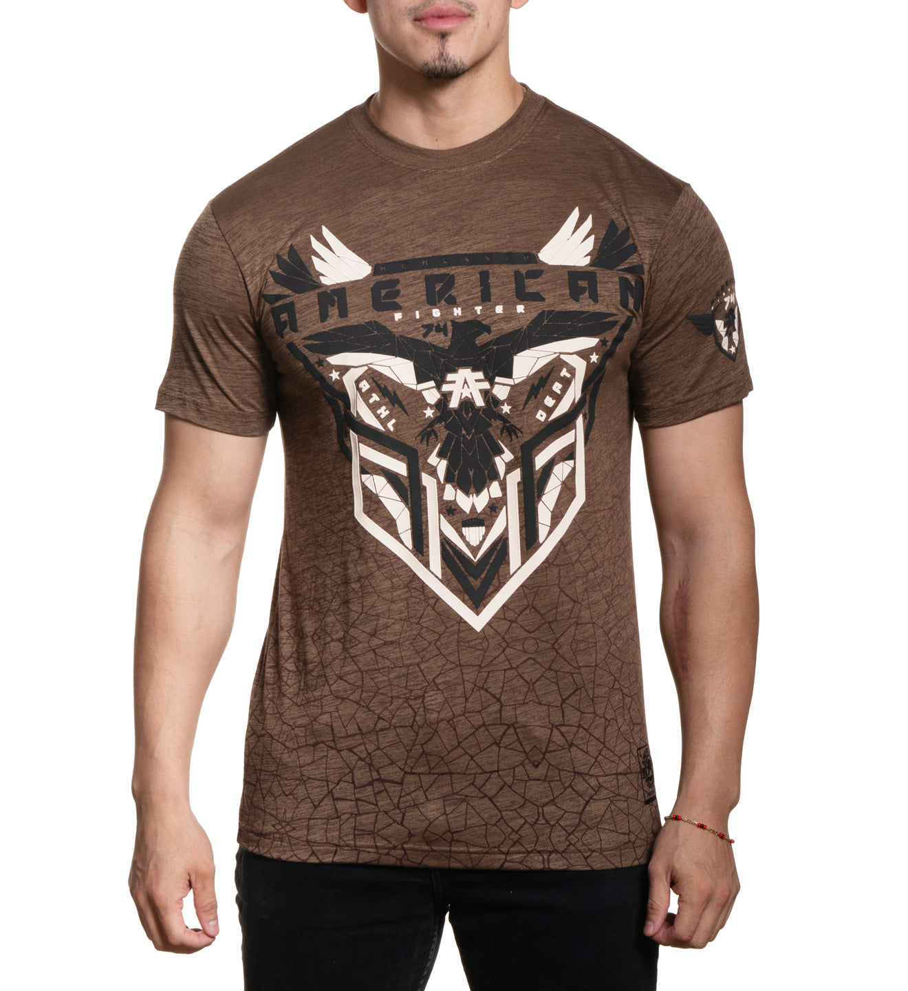 A male model wearing a brown short-sleeved t-shirt with a graphic print of a bull and the word 'AMERICAN' on it.