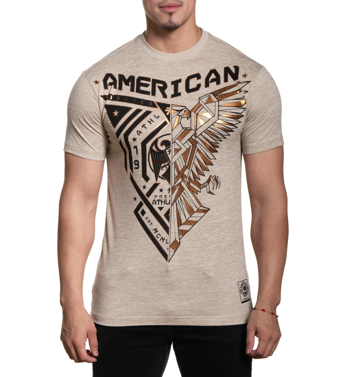 A male model wearing a beige t-shirt with 'AMERICAN' and an eagle graphic printed on the front.